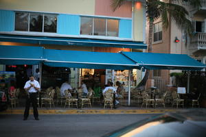 building, cafe, canopy, chair, dusk, eye level view, Florida, man, Miami, object, people, sitting, standing, street, table, The United States, winter